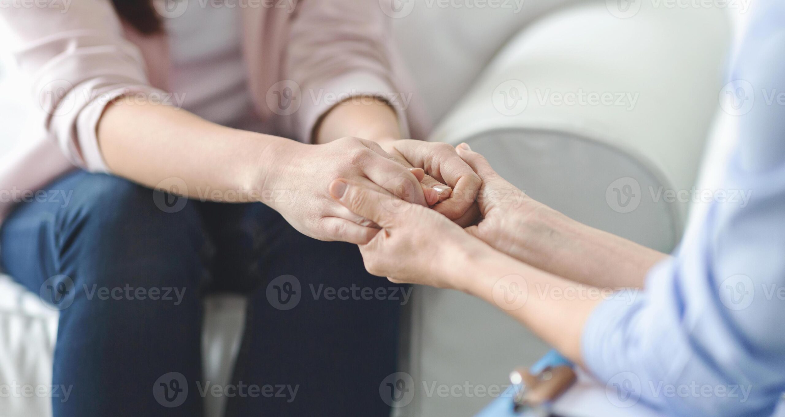 Two people holding hands in a gesture of support and care.